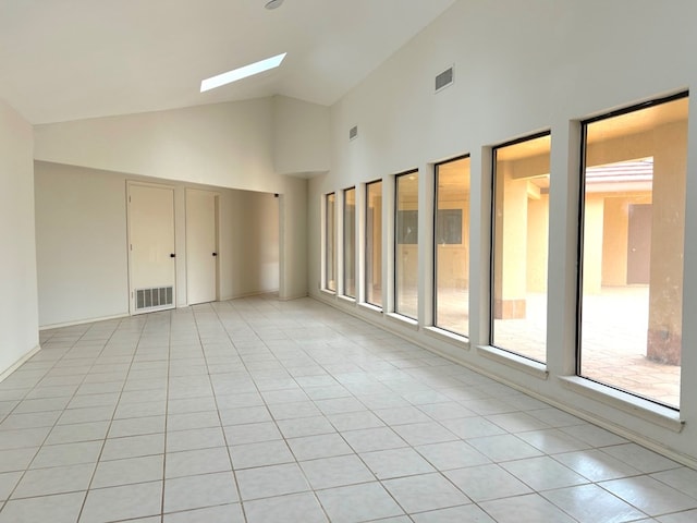 tiled spare room with high vaulted ceiling and a skylight