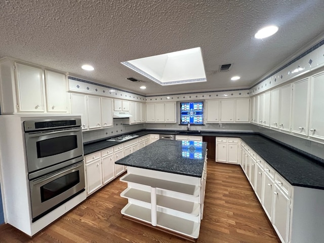 kitchen with dark hardwood / wood-style flooring, a kitchen island, white cabinetry, and gas cooktop