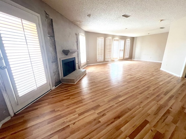 unfurnished living room featuring light hardwood / wood-style flooring and a textured ceiling