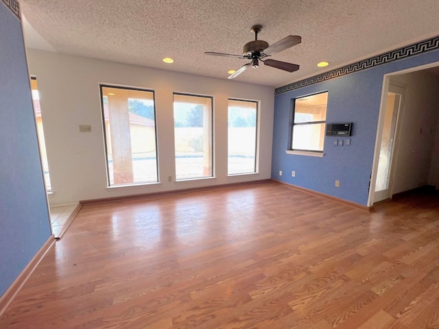 spare room featuring ceiling fan, light wood-type flooring, and a textured ceiling