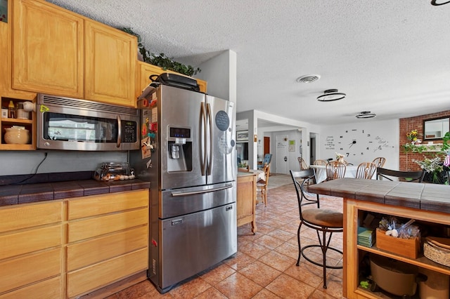 3811 Cimmaron Ave, Midland, TX 79707 - kitchen with stainless steel appliances, tile counters, a textured ceiling, and open shelves