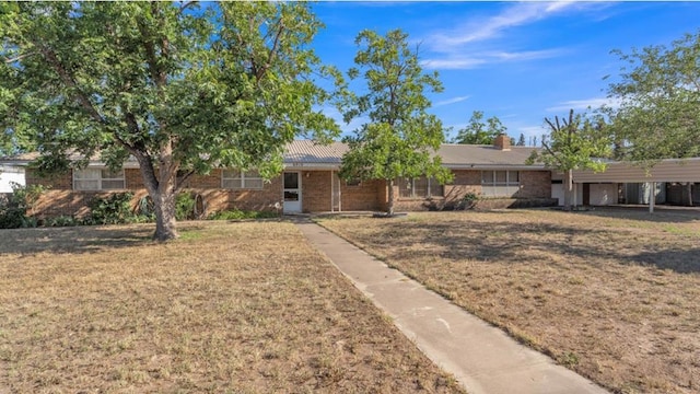 ranch-style home featuring brick siding, an attached carport, and a front yard