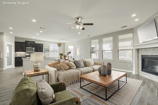 6913 Mcpherson Ln, Midland, TX 79706 - living area featuring a ceiling fan, recessed lighting, light wood-style floors, a fireplace, and baseboards
