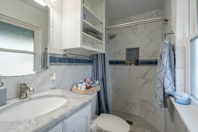 full bath featuring vanity, toilet, tiled shower, and a wealth of natural light