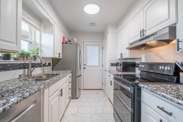 kitchen featuring a sink, marble finish floor, backsplash, under cabinet range hood, and black appliances