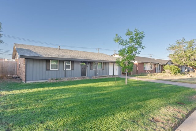 single story home with a shingled roof, a front lawn, board and batten siding, and fence
