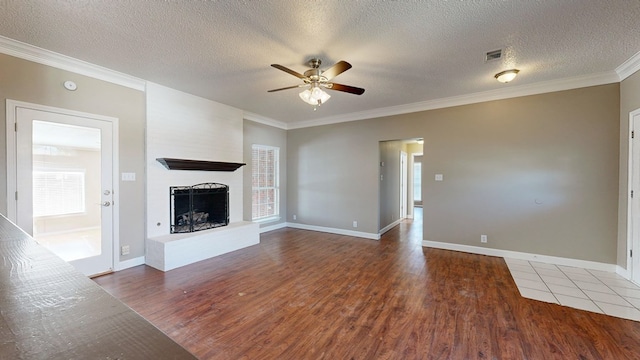 3304 Claremont Dr, Midland, TX 79707 - unfurnished living room featuring a ceiling fan, wood finished floors, a large fireplace, crown molding, and a textured ceiling