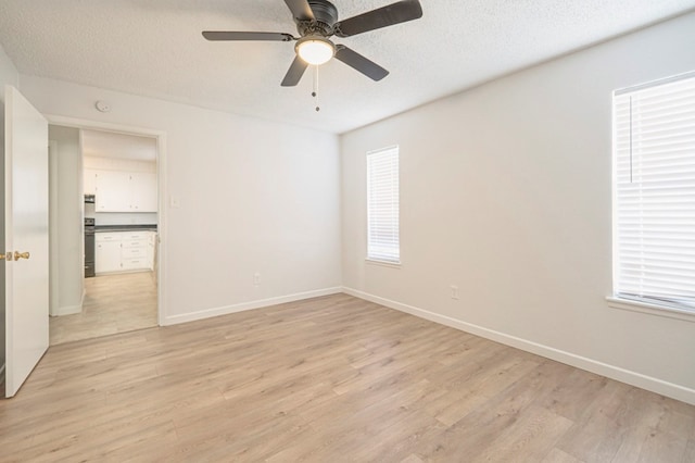 unfurnished room featuring a wealth of natural light, a textured ceiling, and light wood-type flooring