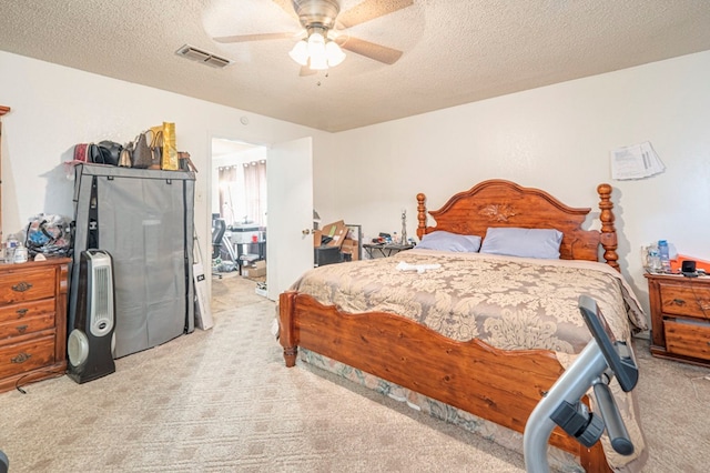 bedroom with ceiling fan, light colored carpet, and a textured ceiling