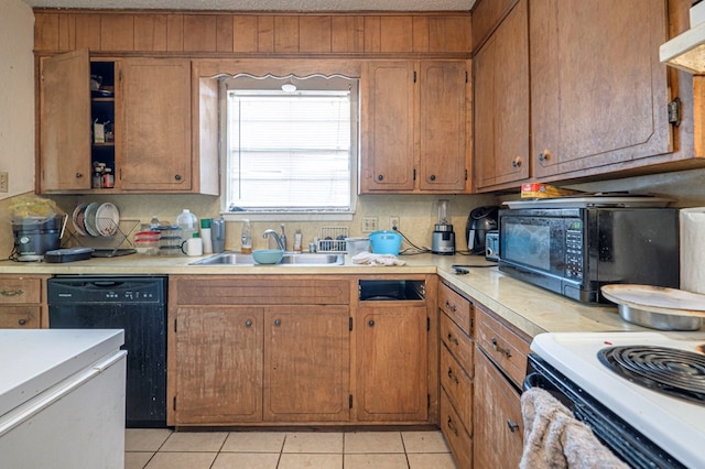 kitchen with light tile patterned floors, sink, a textured ceiling, and black appliances