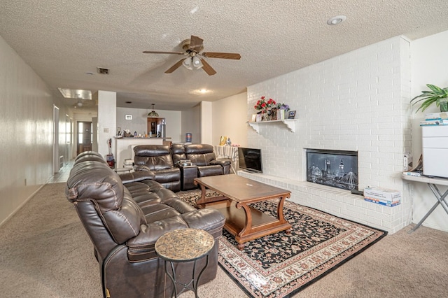 living room with a brick fireplace, ceiling fan, a textured ceiling, and carpet