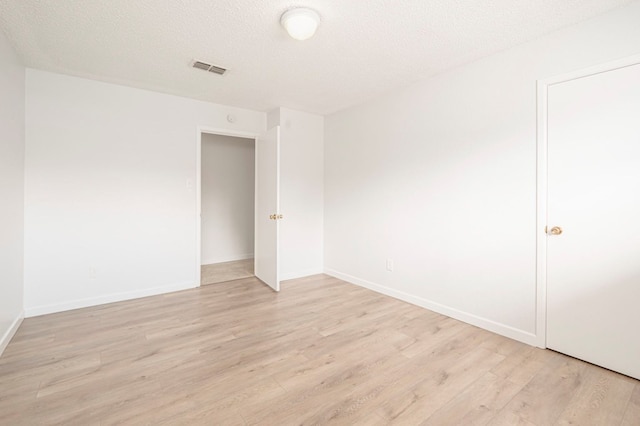 empty room with light hardwood / wood-style floors and a textured ceiling