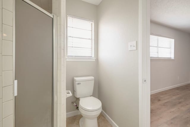 bathroom featuring toilet, a shower with shower door, and hardwood / wood-style floors