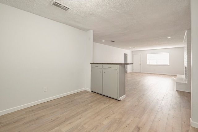 unfurnished room with light hardwood / wood-style floors and a textured ceiling