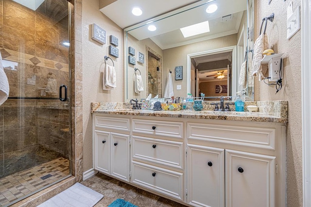 full bathroom with double vanity, ornamental molding, a textured wall, a shower stall, and a skylight