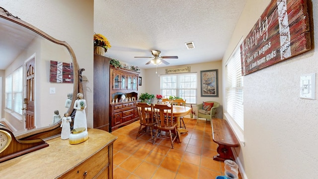 dining area featuring a textured wall, light tile patterned floors, a textured ceiling, a ceiling fan, and visible vents
