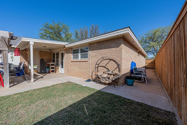 rear view of property with a patio area, brick siding, a fenced backyard, and a lawn