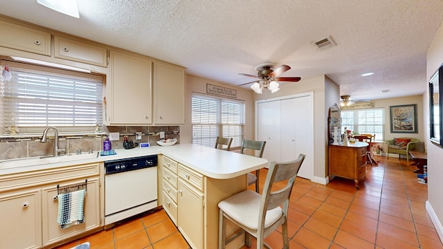 kitchen with ceiling fan, a peninsula, visible vents, dishwasher, and a sink