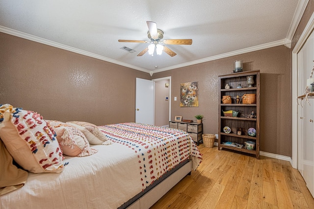 bedroom featuring ornamental molding, a textured wall, light wood-style floors, visible vents, and ceiling fan