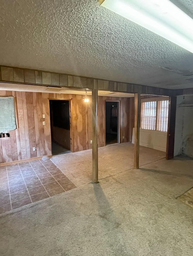 basement with carpet, a textured ceiling, and wooden walls