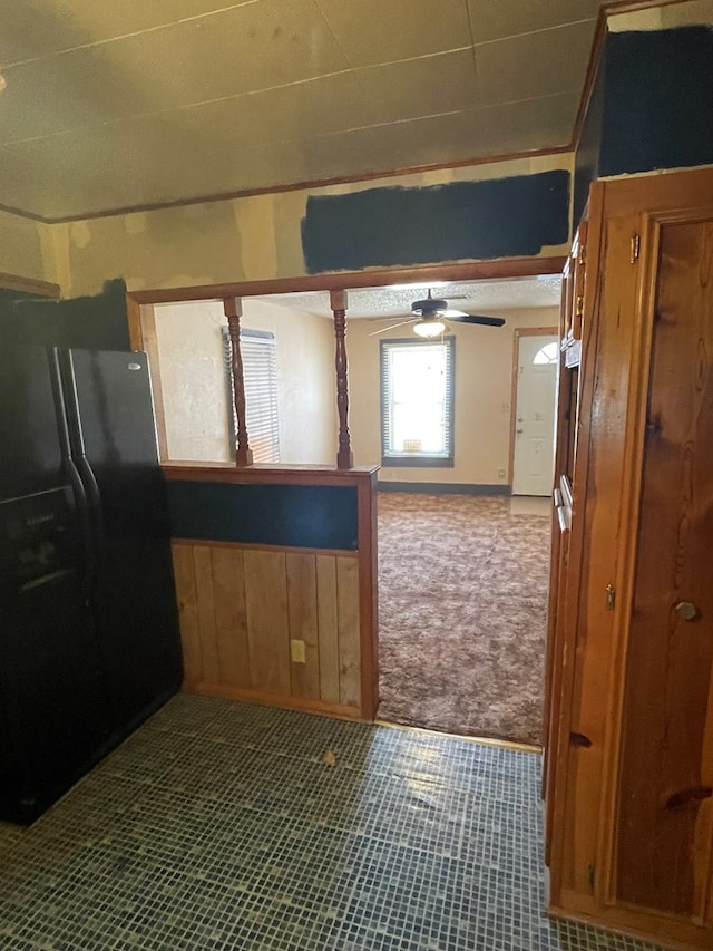 kitchen featuring carpet, ceiling fan, wood walls, and black fridge with ice dispenser