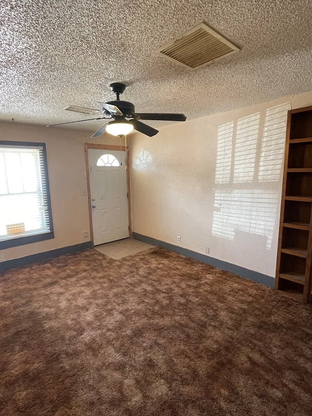 foyer entrance featuring ceiling fan, carpet, and a textured ceiling