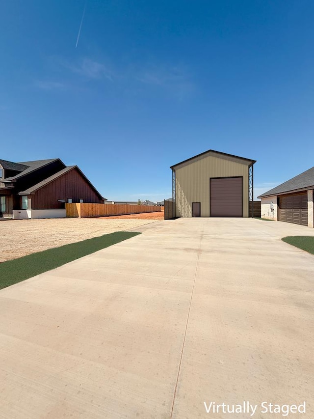 exterior space featuring a garage, fence, and an outdoor structure