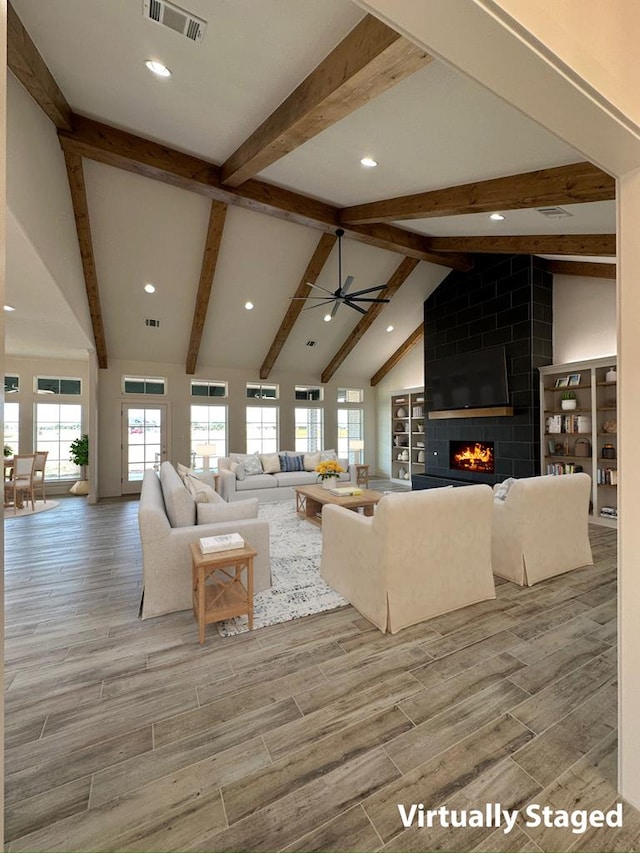 living room featuring wood tiled floor, visible vents, a wealth of natural light, and a tile fireplace