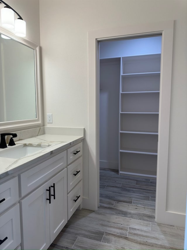 bathroom featuring a walk in closet, wood finish floors, and vanity