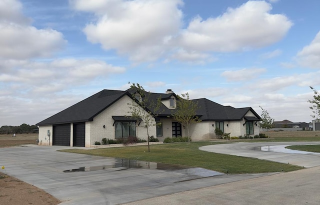 french country style house with a garage, a front yard, and concrete driveway