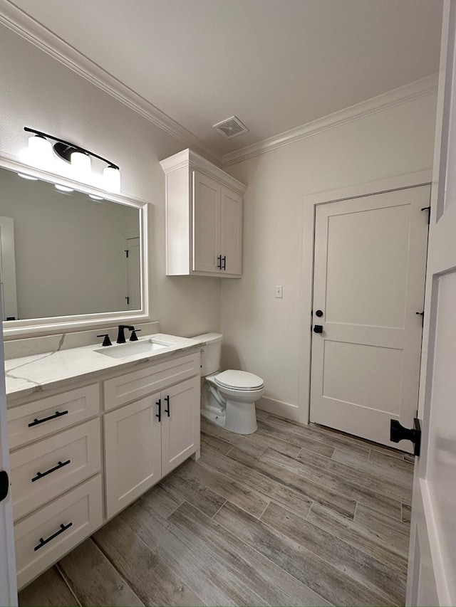 bathroom featuring vanity, toilet, wood-type flooring, and ornamental molding