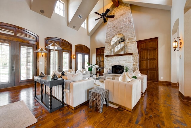 living room with a towering ceiling, a fireplace, ceiling fan, and dark hardwood / wood-style floors