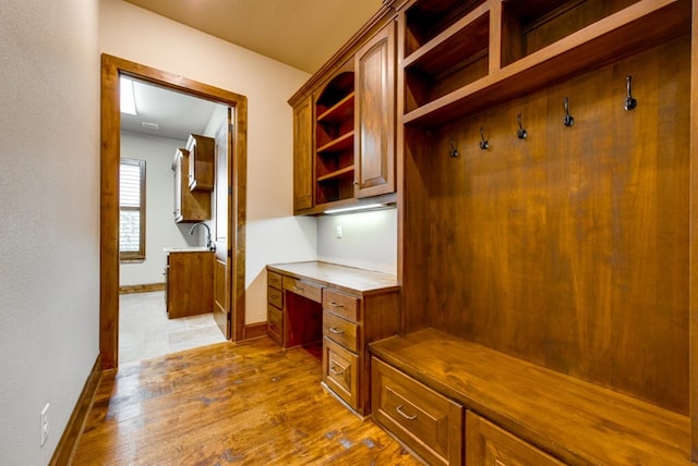 mudroom with built in desk, light hardwood / wood-style flooring, and sink