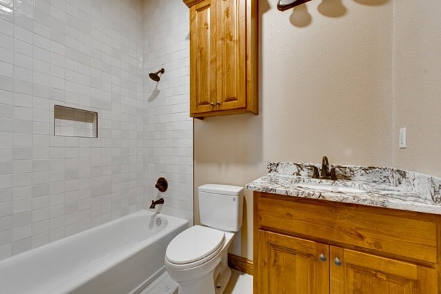 full bathroom featuring toilet, vanity, and tiled shower / bath