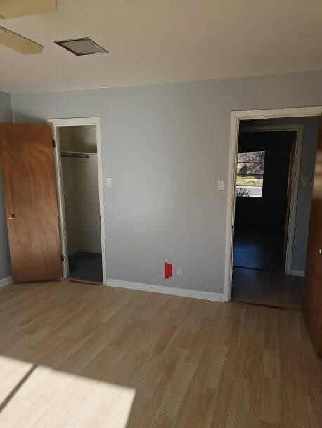 unfurnished bedroom with ceiling fan, a closet, and wood-type flooring