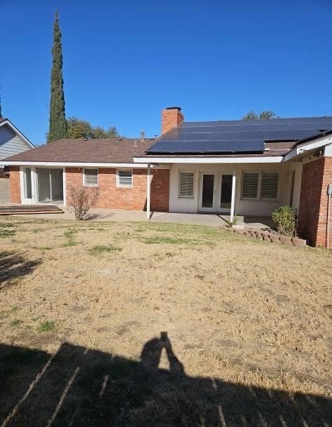 back of house with solar panels and a patio