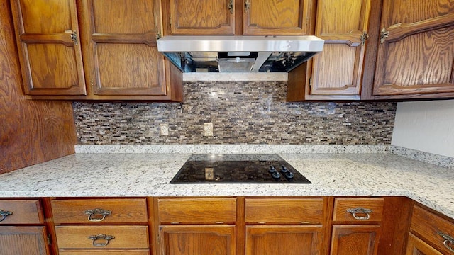 4203 Skyline Dr, Midland, TX 79707 - kitchen featuring wall chimney range hood, black electric stovetop, brown cabinetry, and tasteful backsplash