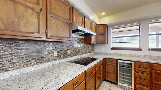 4203 Skyline Dr, Midland, TX 79707 - kitchen featuring wine cooler, under cabinet range hood, black electric cooktop, backsplash, and brown cabinetry