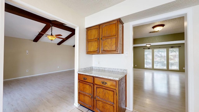 4203 Skyline Dr, Midland, TX 79707 - kitchen featuring open floor plan, light wood-style floors, a ceiling fan, beamed ceiling, and brown cabinets