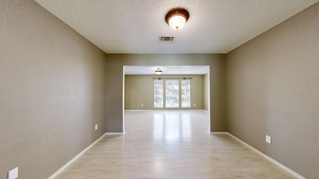 4203 Skyline Dr, Midland, TX 79707 - empty room with light wood-style floors, a textured ceiling, a textured wall, and baseboards