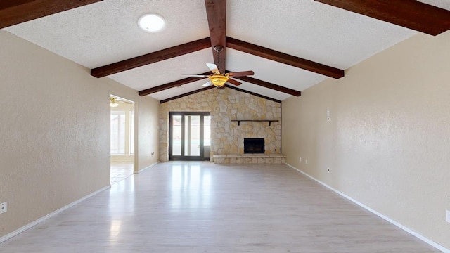 4203 Skyline Dr, Midland, TX 79707 - unfurnished living room with light wood finished floors, a ceiling fan, a stone fireplace, a textured wall, and baseboards