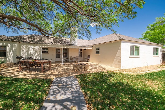 back of property with a lawn, an outdoor fire pit, and a patio