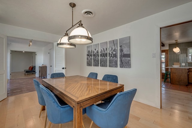 dining area with light wood-style floors and visible vents