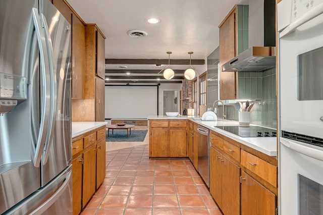 kitchen featuring a sink, light countertops, a peninsula, stainless steel appliances, and wall chimney exhaust hood