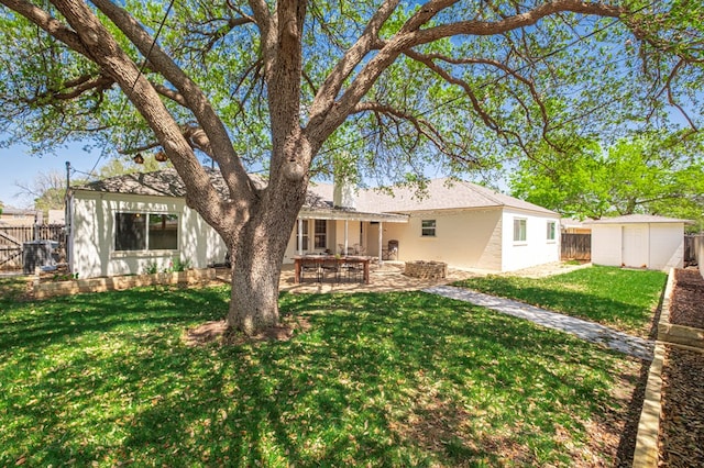 rear view of property featuring a patio area, a fenced backyard, a storage unit, a yard, and stucco siding