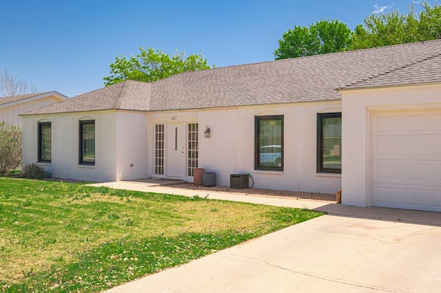 single story home featuring concrete driveway, brick siding, a front yard, and roof with shingles