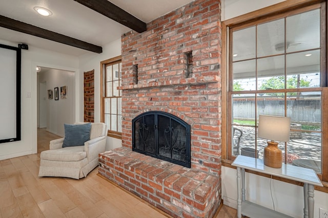 living area featuring beamed ceiling, wood finished floors, and a fireplace