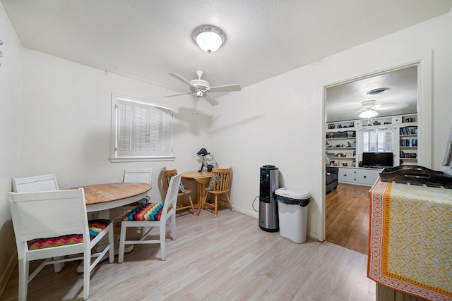 dining space featuring ceiling fan, built in features, and light wood-type flooring