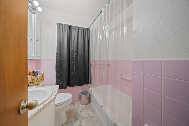 bathroom featuring vanity, toilet, and tile walls