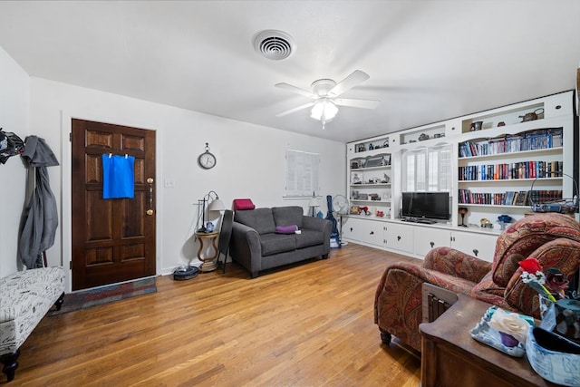 living room featuring ceiling fan, light hardwood / wood-style flooring, and built in features